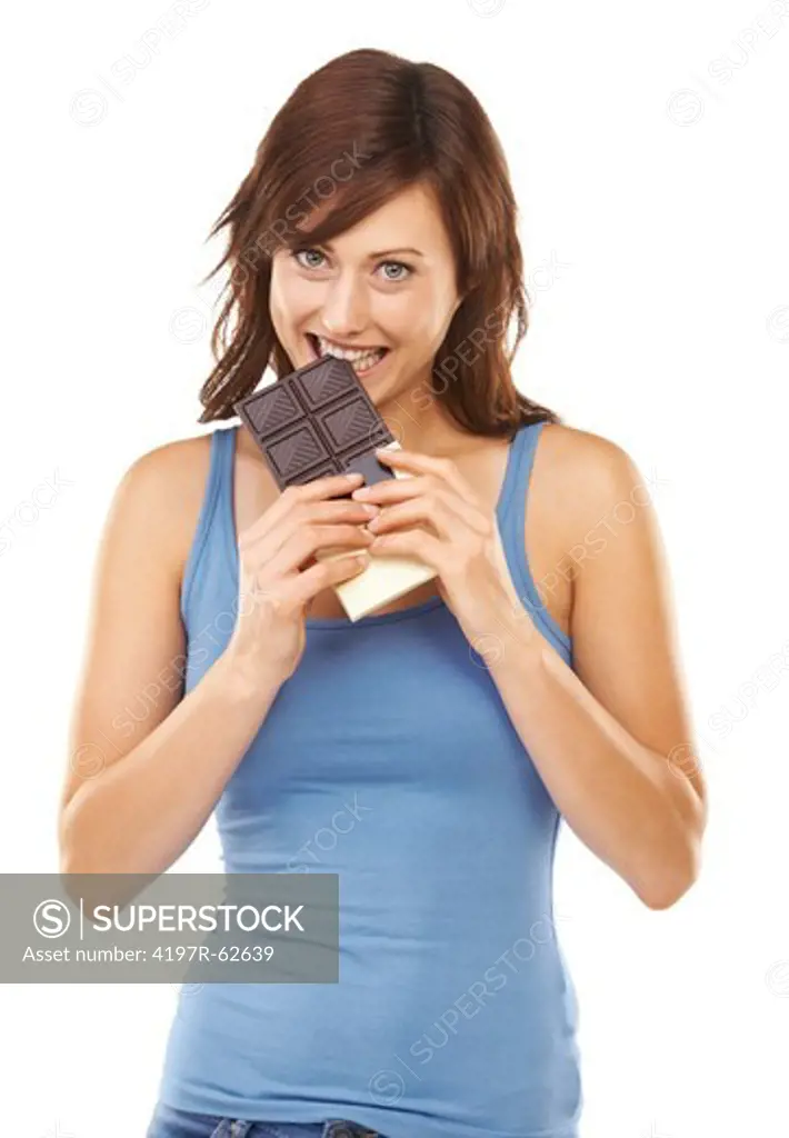 Playful studio portrait of a young woman taking a bite out of a huge chocolate bar isolated on white