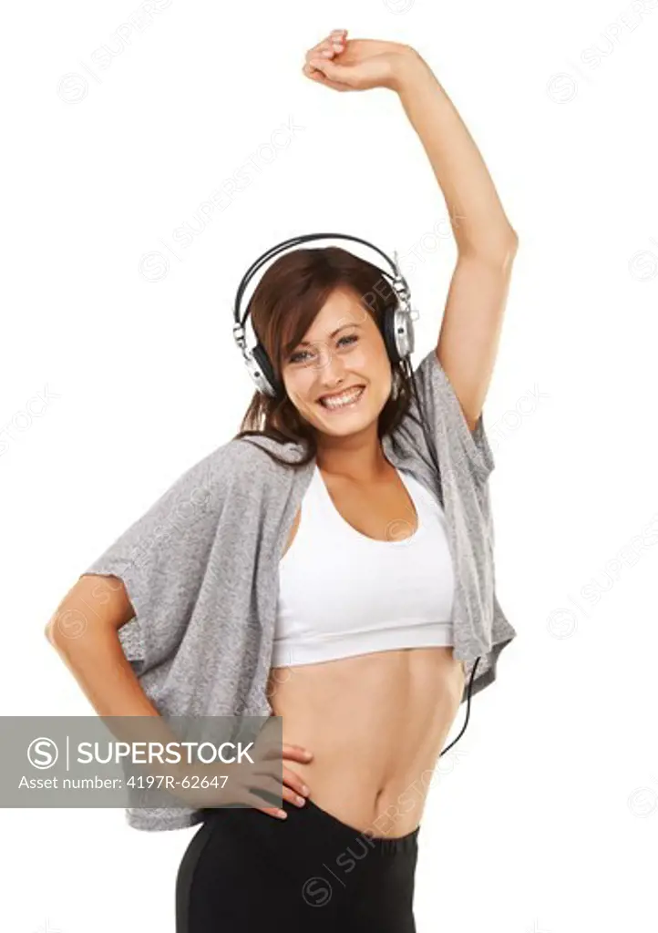 Sideways studio shot of a sporty young woman wearing headphones and dancing with one arm over her head isolated on white