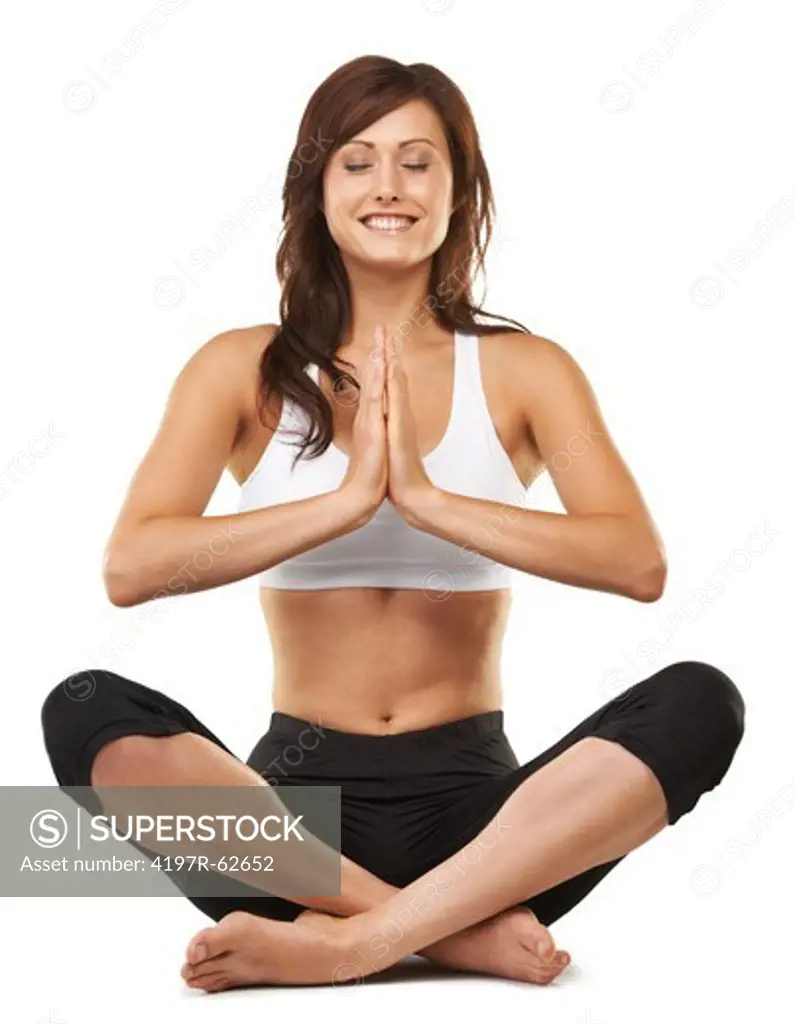 Studio shot of an attractive young woman sitting cross-legged in a meditative posture isolated on white