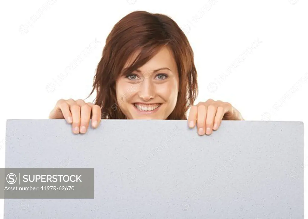 Studio portrait or an attractive young woman holding up a blank sign from behind isolated on white