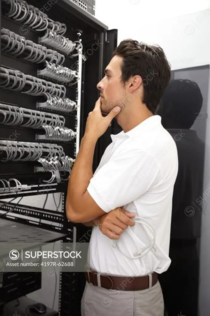 Thoughtful young IT technician working in a server room