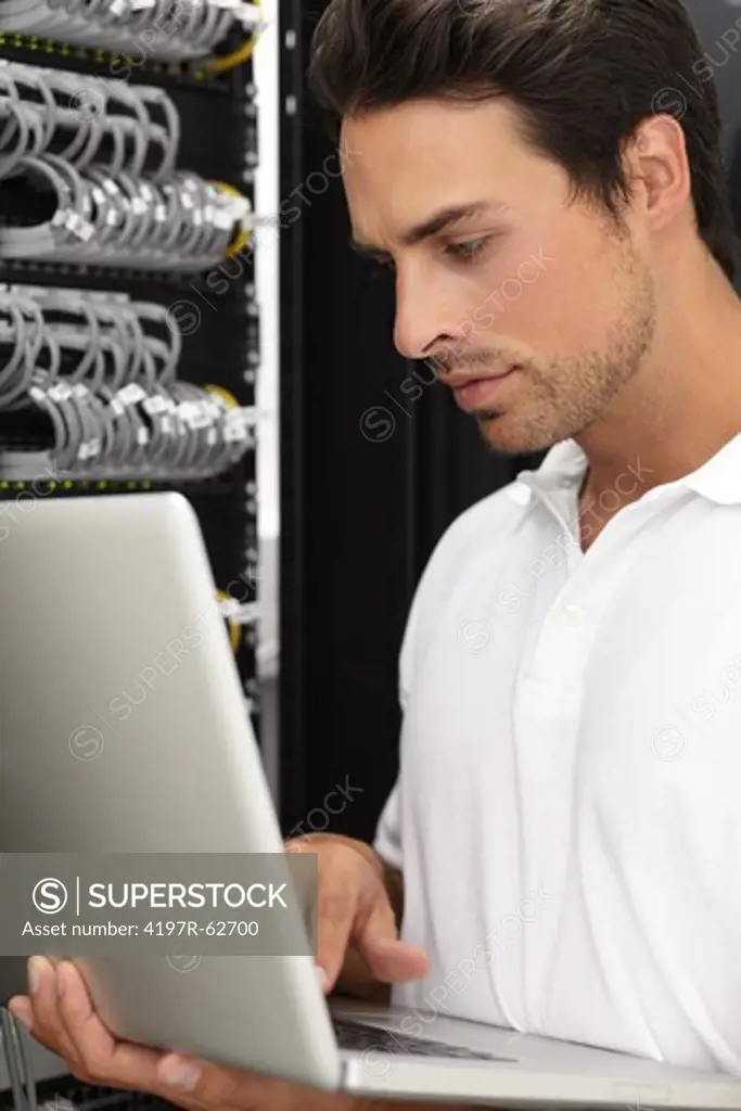 Young IT consultant working in a server room on his laptop