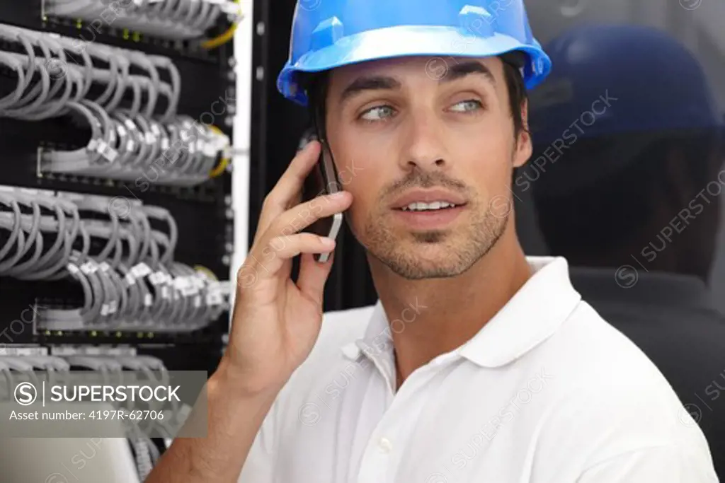 Professional young IT consultant working in a server room and using his cellphone