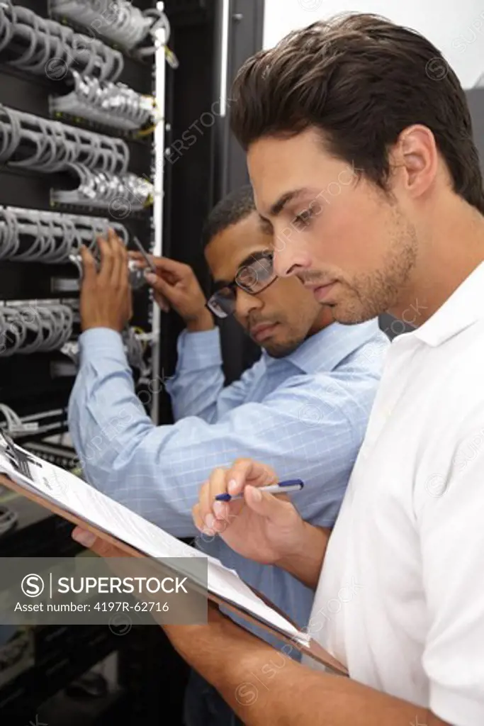 Focused young IT consultants working in a server room