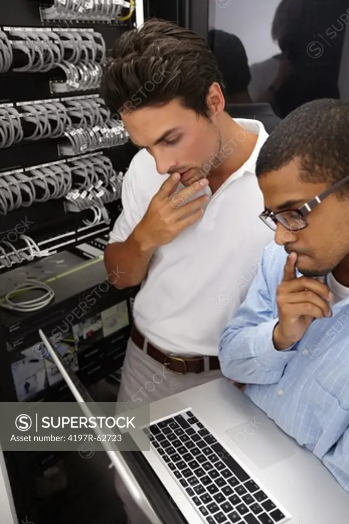 Two young IT specialists hard at work in a server room to fix an issue