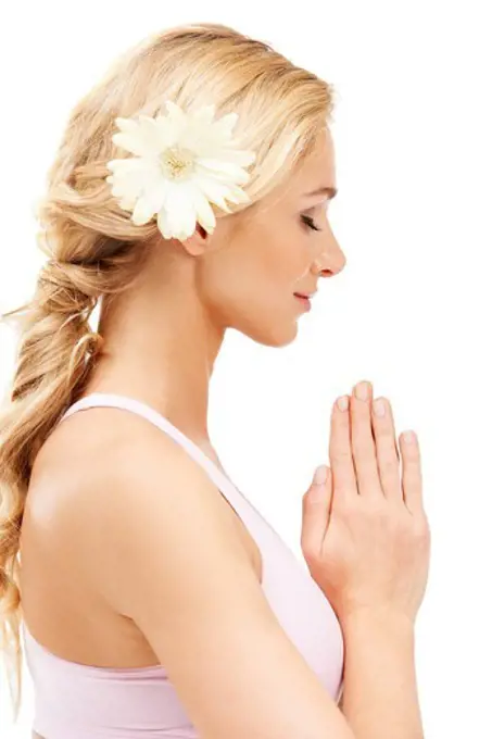 A young beauty with a flower in her hair meditating while isolated on a white background