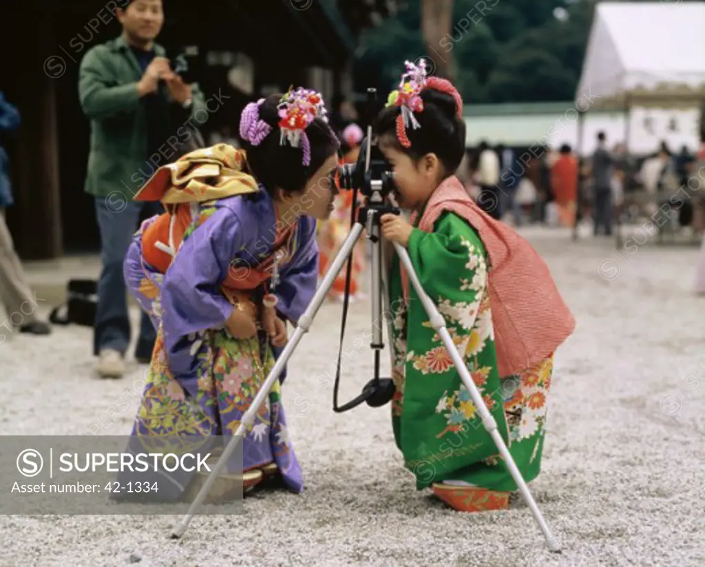 Two girls looking through a camera, Shichi Go San, Meiji-Jingu Shrine, Tokyo, Japan