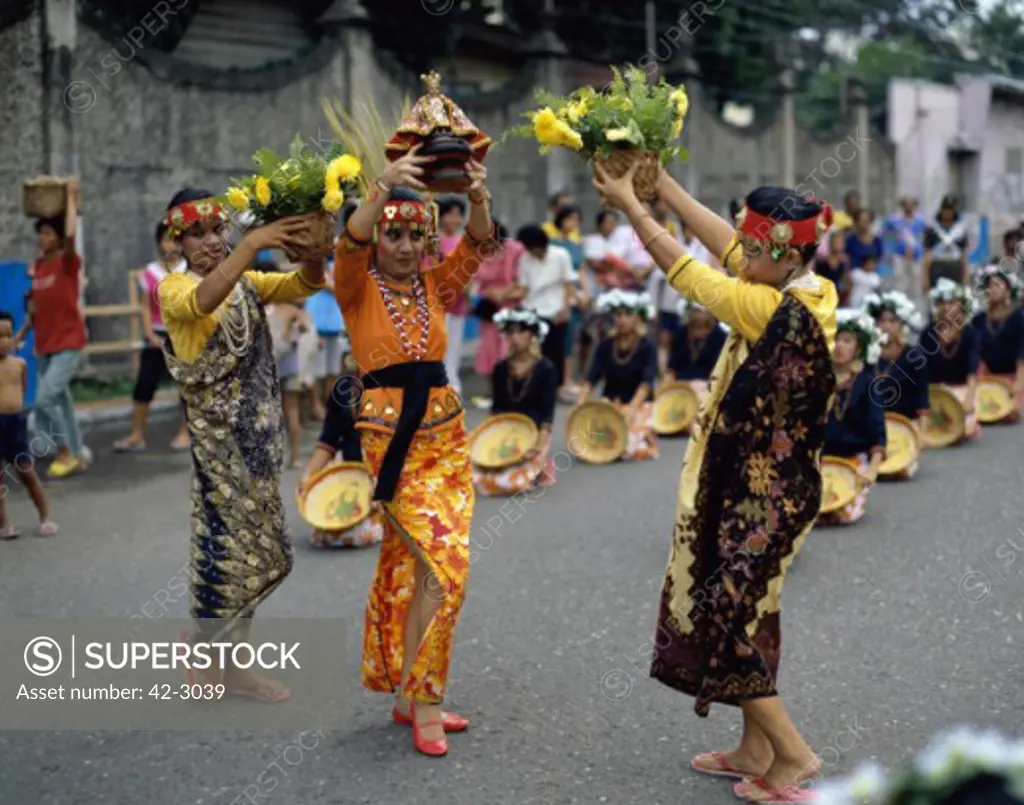 Three mid adult women dancing on a road, Sinulog Festival, Cebu, Philippines