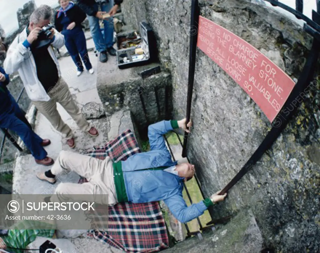 High angle view of a man kissing a stone wall, Blarney Stone, County Cork, Ireland