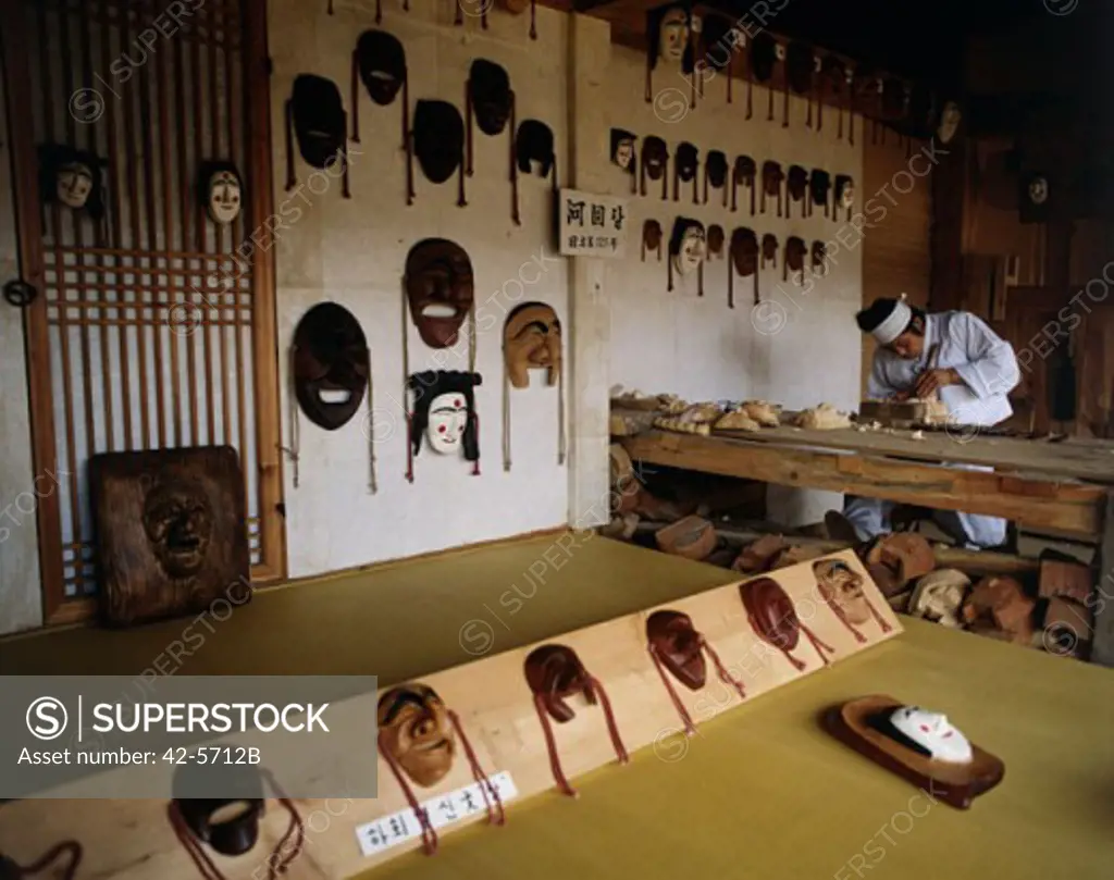 Mid adult man working on wooden masks, Korean Folk Village, Seoul, South Korea