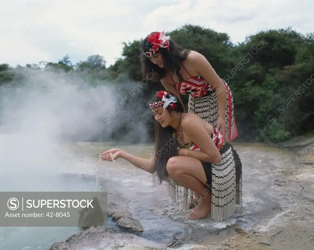 Two young Maori women cooking in a thermal pool, Rotorua, North Island, New Zealand
