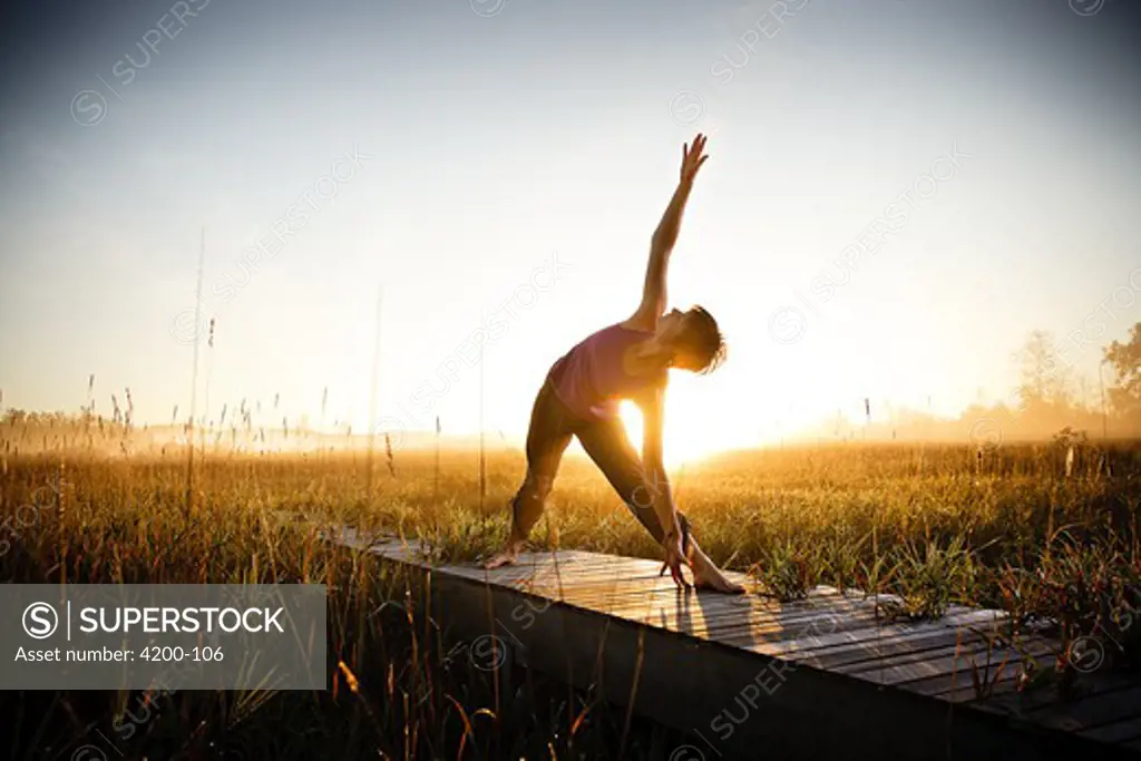 Mid adult woman practicing yoga at sunset