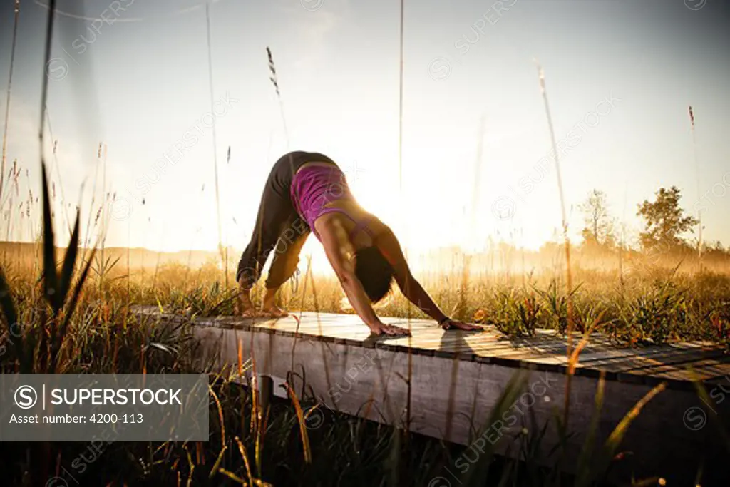 Mid adult woman practicing yoga at sunset