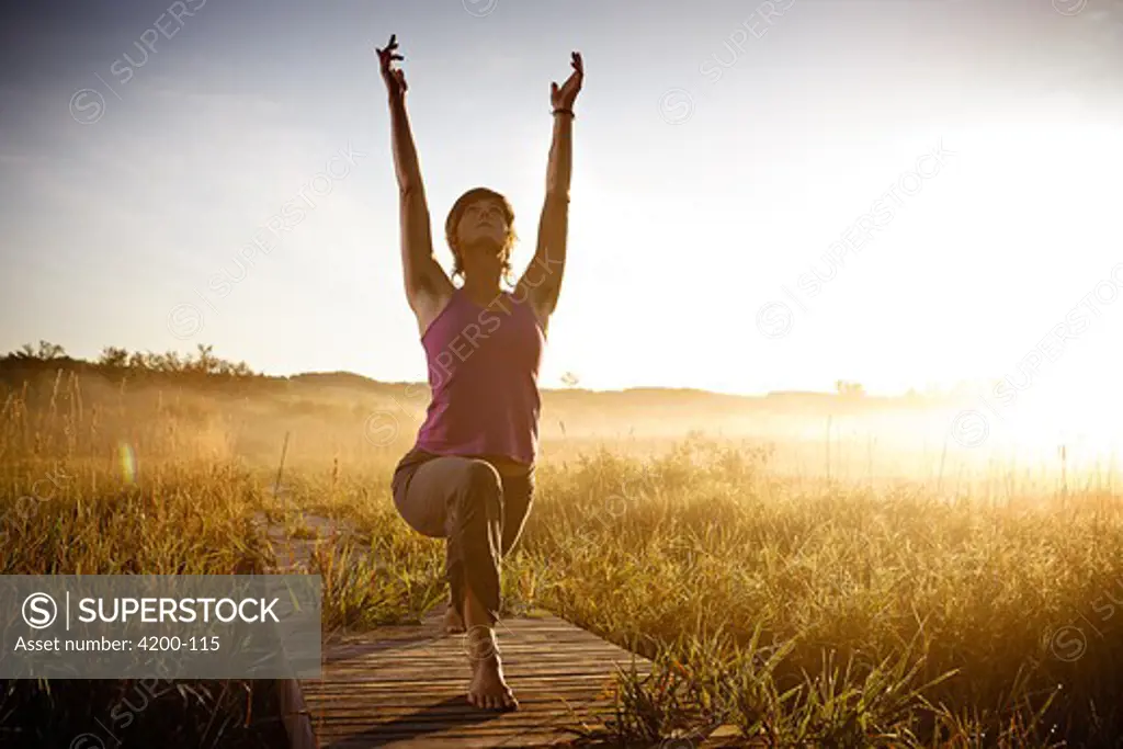 Mid adult woman practicing yoga at sunset