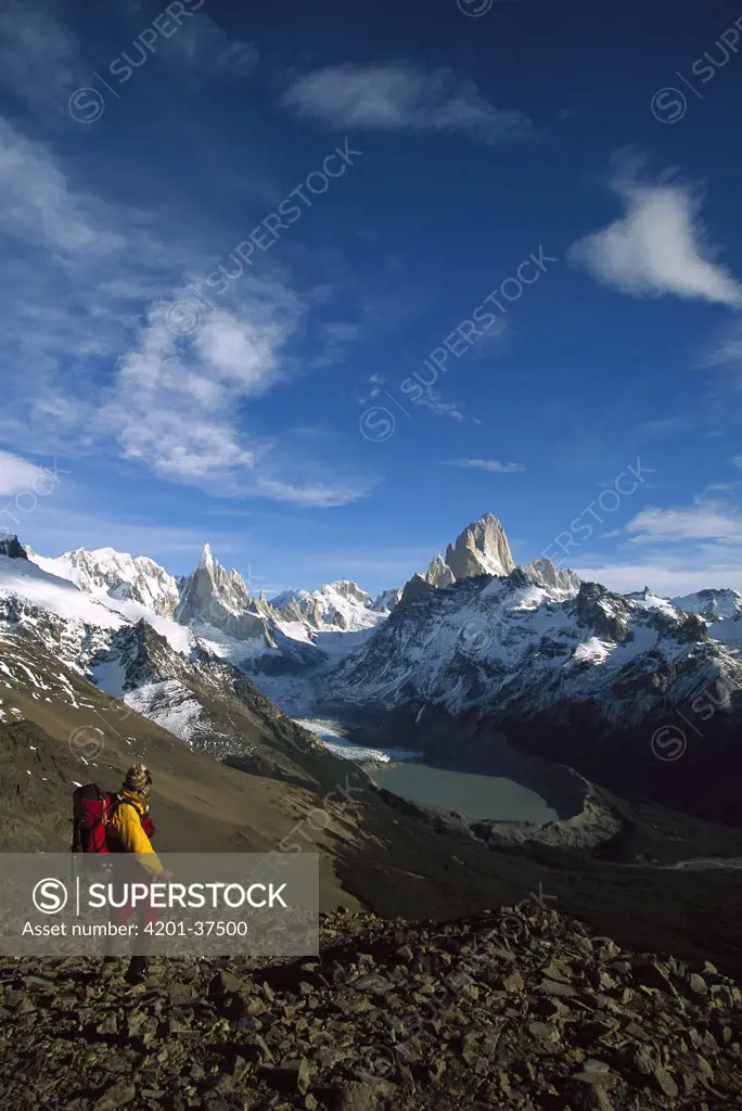 Hiker on Loma Plieque Tumbado admiring the view of Cerro Torre, left, and Fitzroy, Los Glaciares National Park, Patagonia, Argentina