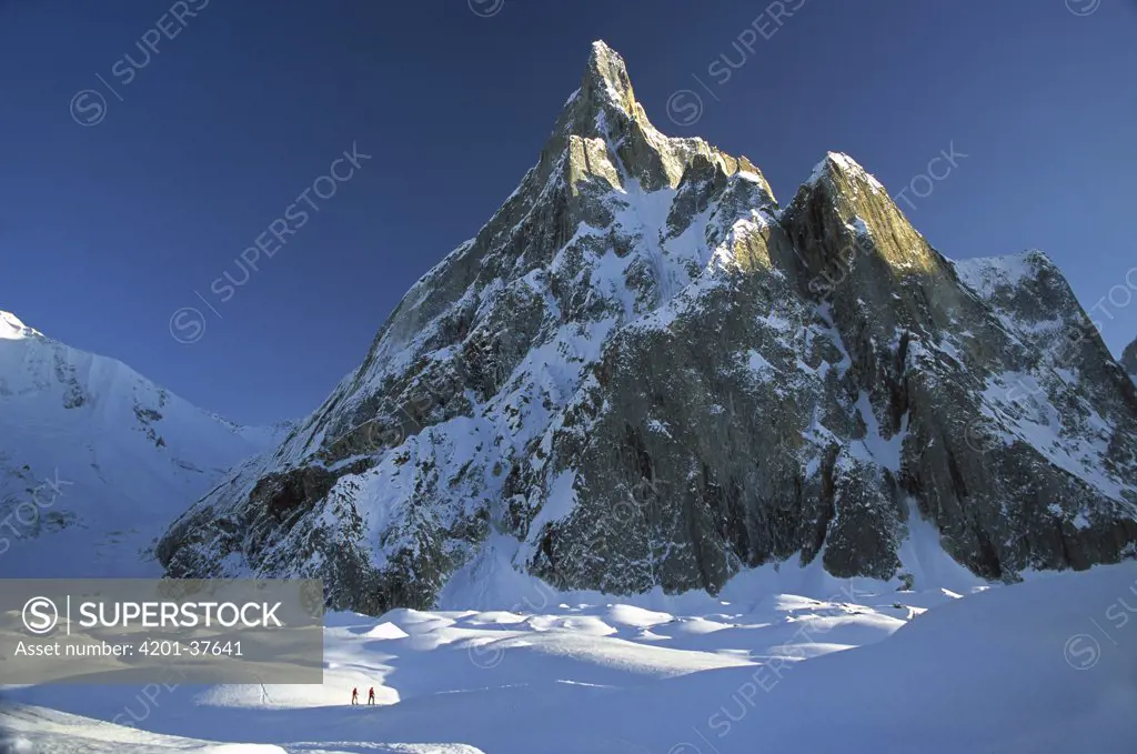 Skiers under rock spire, unnamed peak near Concordia, Baltoro Glacier, Karakoram Mountains, Pakistan