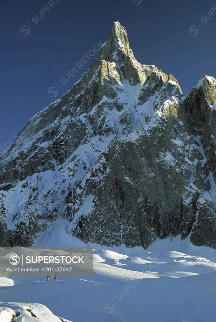 Skiers under rock spire, unnamed peak near Concordia, Baltoro Glacier, Karakoram Mountains, Pakistan