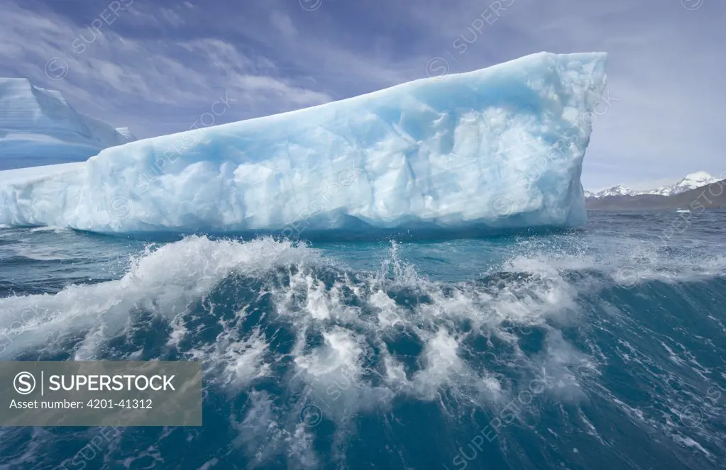 Massive iceberg floating, smashing into waves and melting rapidly due to gobal warming and rising temperatures of sea and air, near Cumberland Bay, South Georgia Island, Southern Ocean, Antarctic Convergence