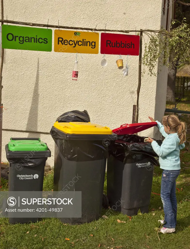 Girl disposes of garbage, recycling, and organic waste into garbage bins, Little River, Banks Peninsula, Canterbury, New Zealand