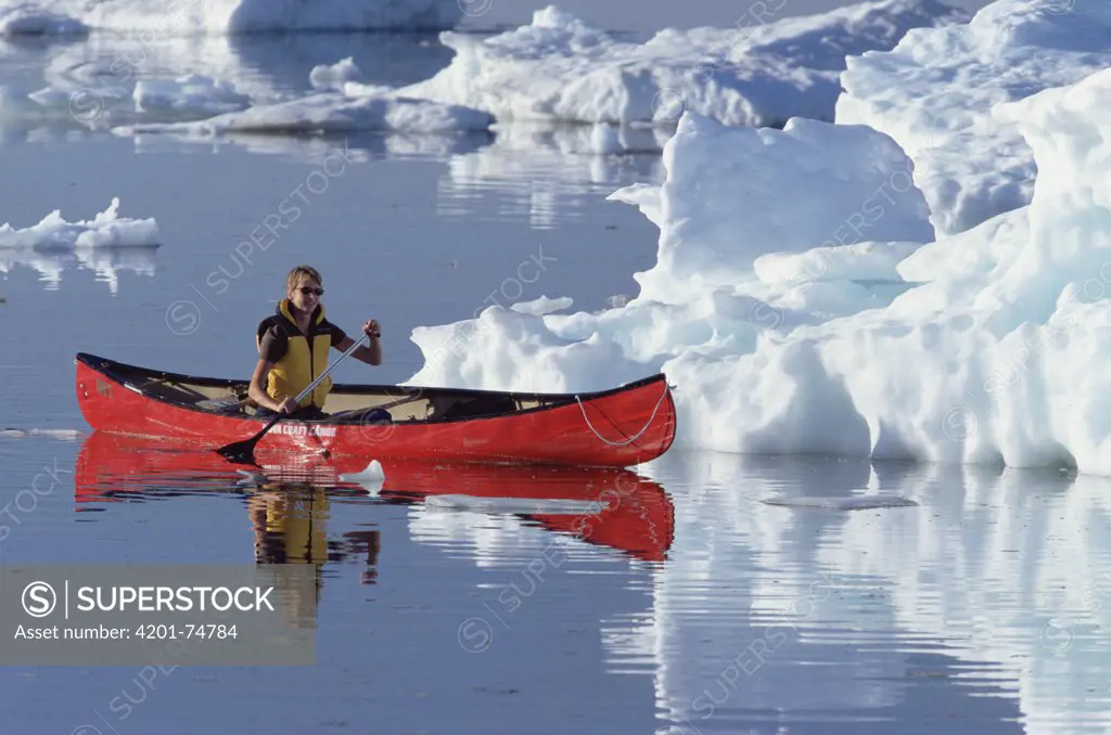 Female canoeist on Hudson Bay among pack ice, Churchill, Manitoba, Canada
