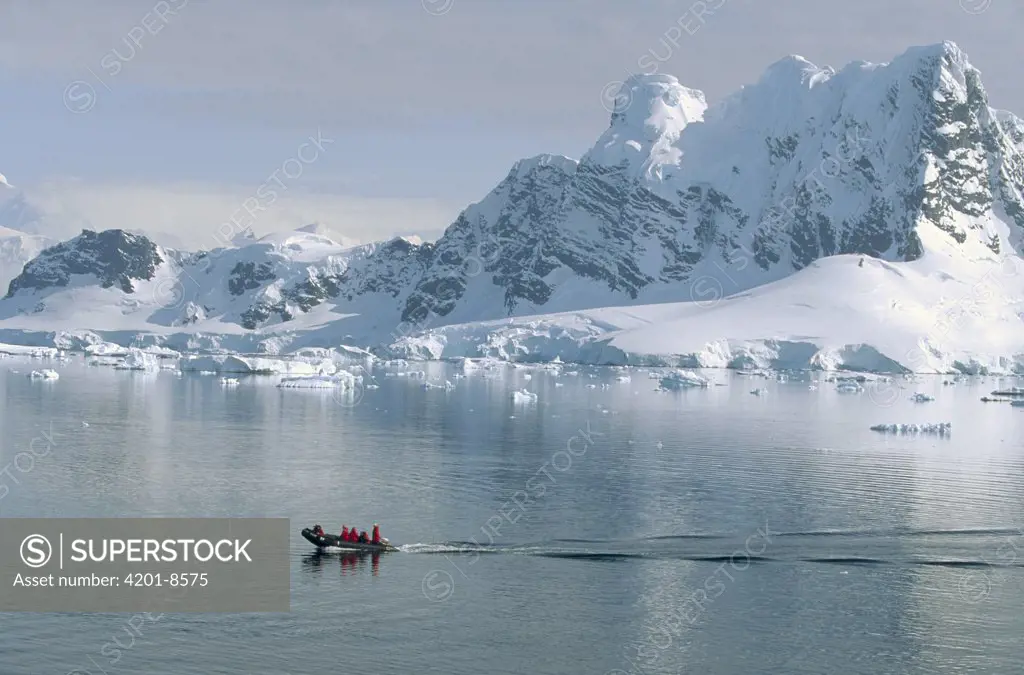 Tourists in zodiac boat with snow covered landscape, Paradise Bay, Antarctica