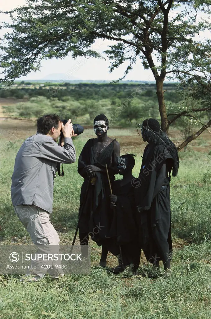 Tourist photographing young Masai tribesmen in typical dress and body paint after circumcision, Tanzania