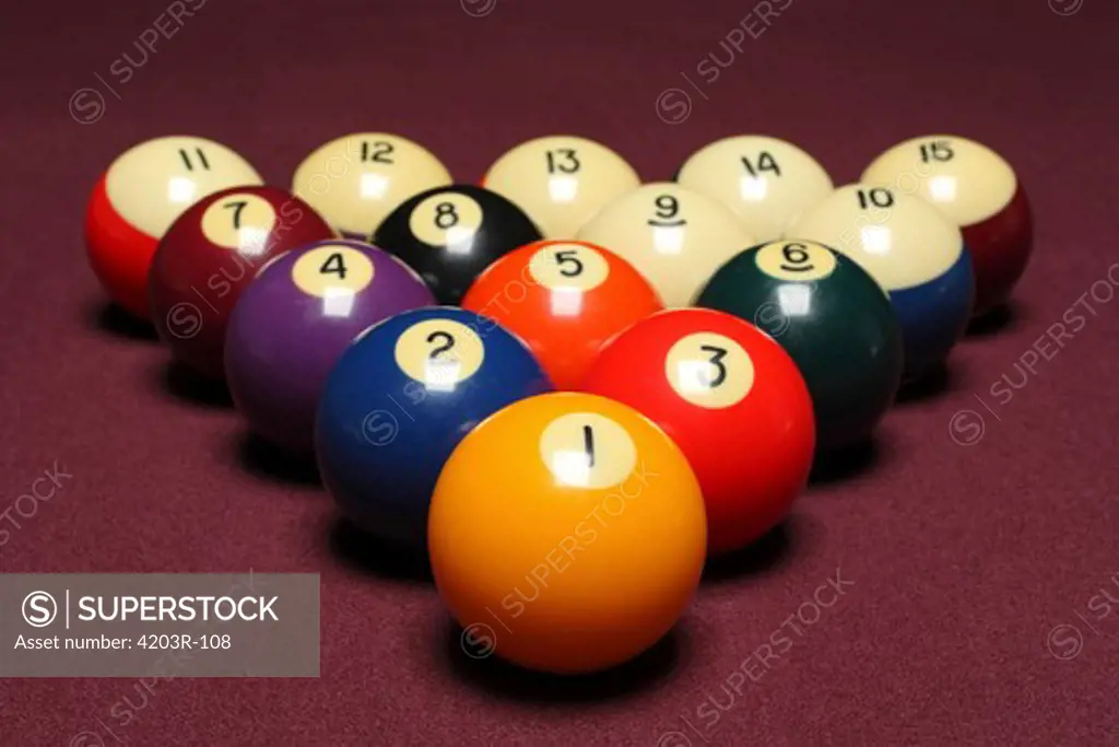 Fifteen billiard balls arranged in triangle on pool table