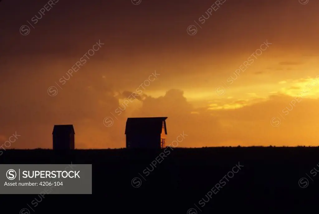 Silhouette of barn and a corncrib at sunset, Iowa, USA
