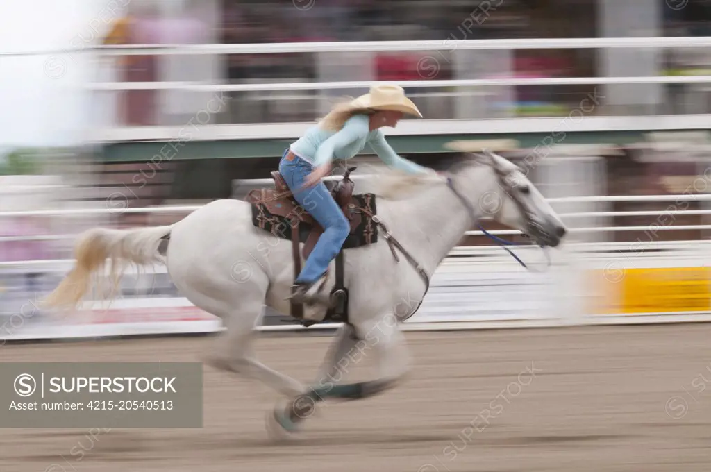 Motion blur of a cowgirl riding fast during barrel racing, Sundre Pro Rodeo, Sundre, Alberta, Canada