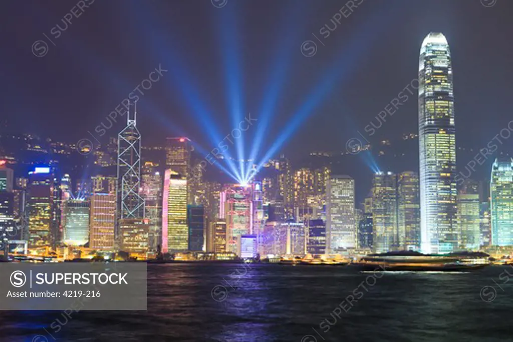 Skyscrapers lit at dusk at waterfront, Victoria Harbour, Hong Kong Island, Kowloon, Hong Kong, China