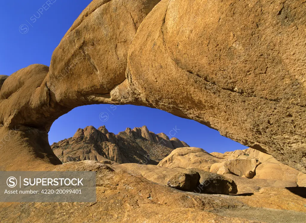 Rock arch - Pandock mountains seen through a rock arch of red granite. Spitzkoppe area, Namibia, Africa.