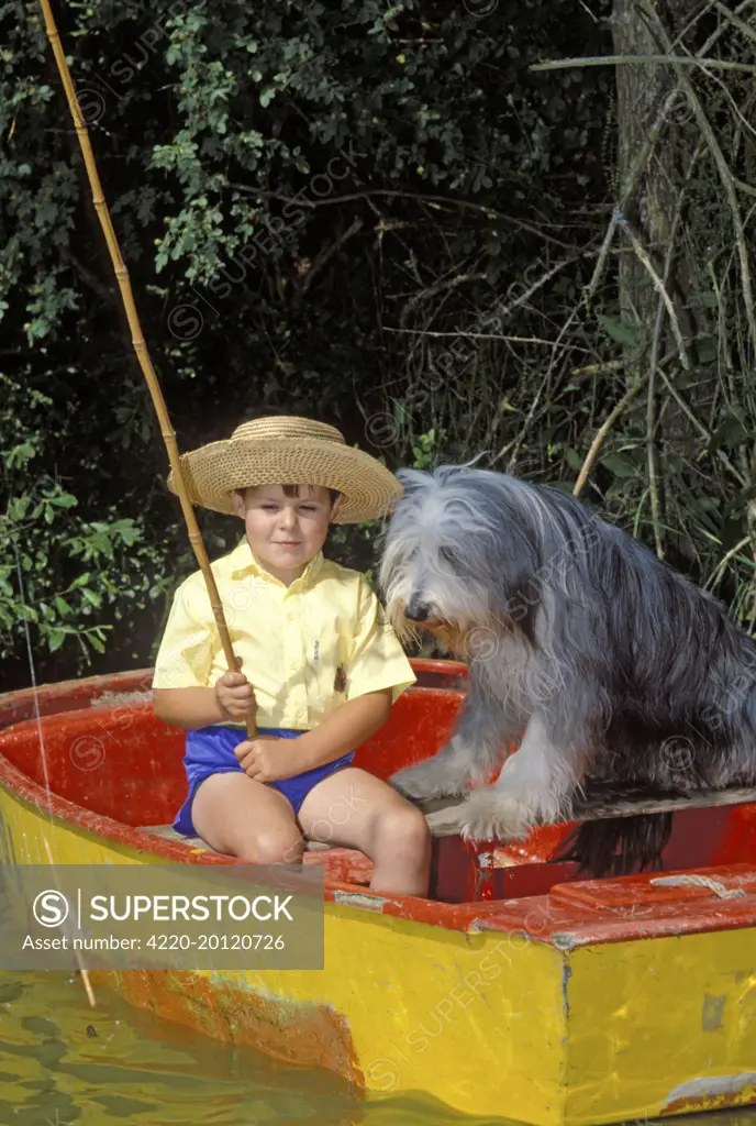 Young boy fishing from boat - with Bearded Collie Dog 