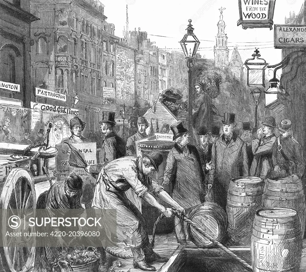 The pavements of London's  Strand are as congested as the  street itself, with street  vendors, a sandwich-man, and a  drayman delivering barrels of  beer to a pub cellar.     Date: 1889