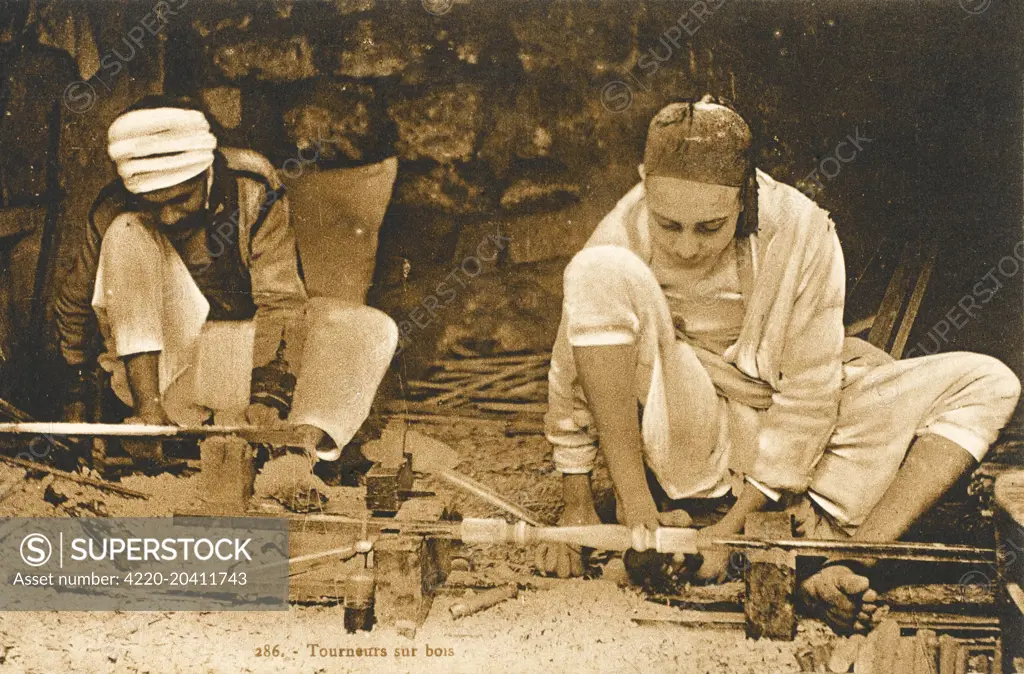 A wood turner in Tunisia, making an elegant table leg - the basic lathe appears to be foot-operated.     Date: circa 1910s