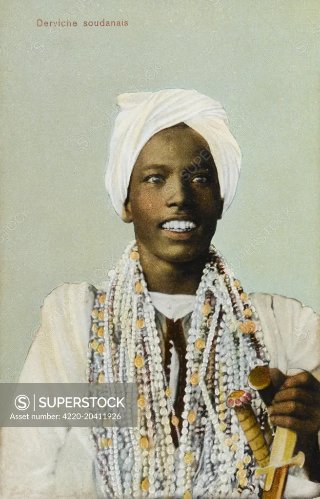 A Young Sudanese Dervish, holding a dagger and grinning widely.     Date: 1910s