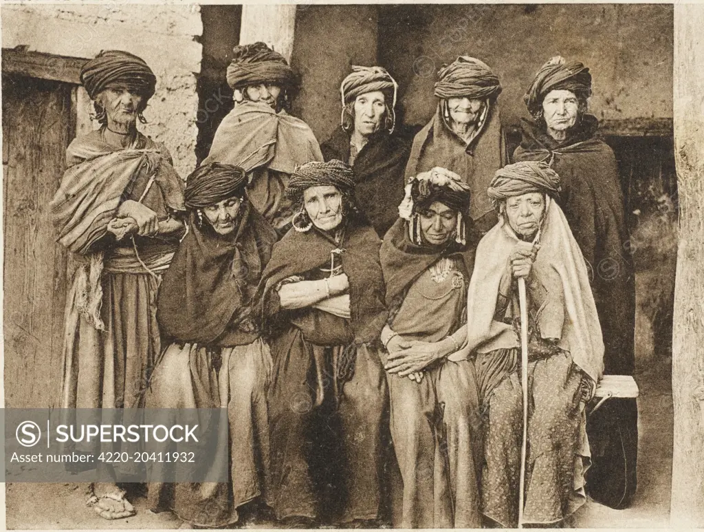 &quot;Berber Golden Oldies&quot; - A group of elderly Algerian Berber Women, heavily wrapped up against the elements, but still displaying traditional costume and jewellery including large hooped earrings.     Date: circa 1910s