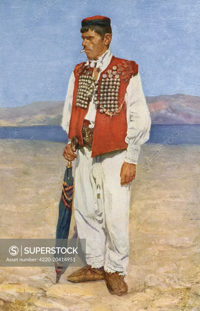 Croatia - Traditional National Costume (6/8) - young man standing on the beach smoking a cigarette. He is holding a furled blue umbrella and wears a red jerkin adorned with silver coins or medallions     Date: circa 1930s