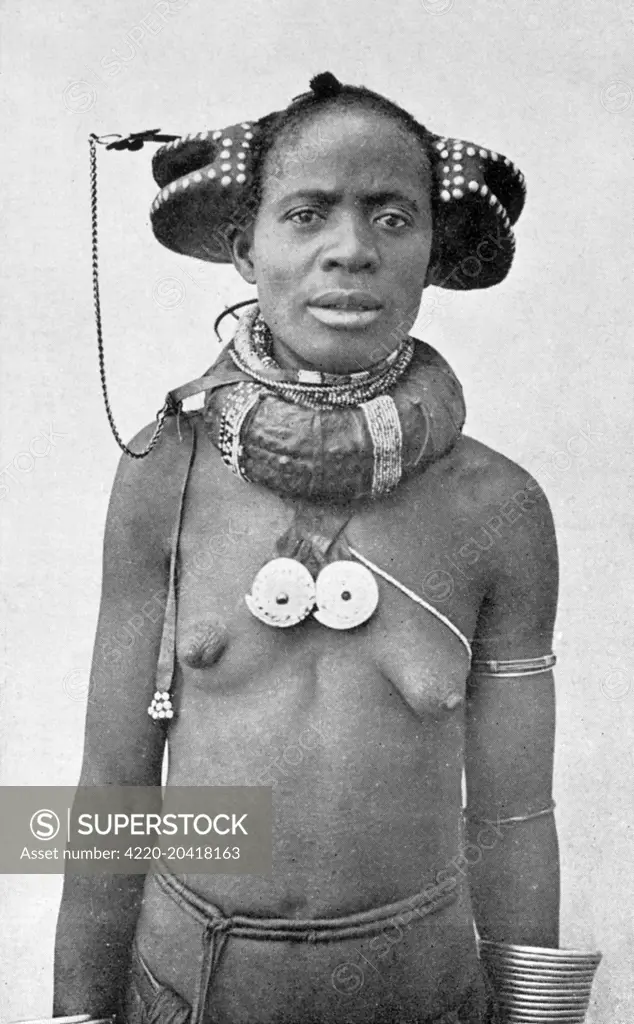 Angola - Woman with the extraordinary hairstyle and neck jewellery/adornment of the region of Huila Province.     Date: circa 1910s