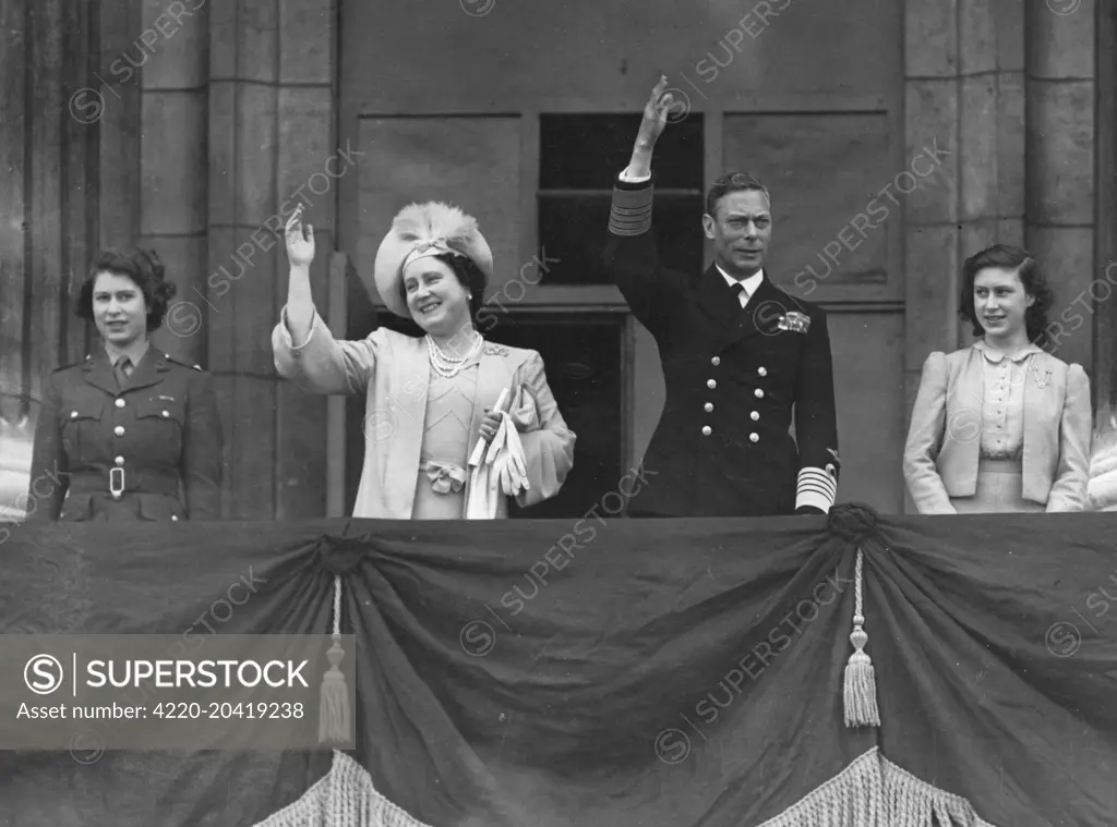 King George VI, Queen Elizabeth (later the Queen Mother) together with their daughters, Princess Elizabeth (later Queen Elizabeth II) in ATS uniform and Princess Margaret Rose on the balcony of Buckingham Palace waving to crowds on VE Day, 8 May 1945.     Date: 1945