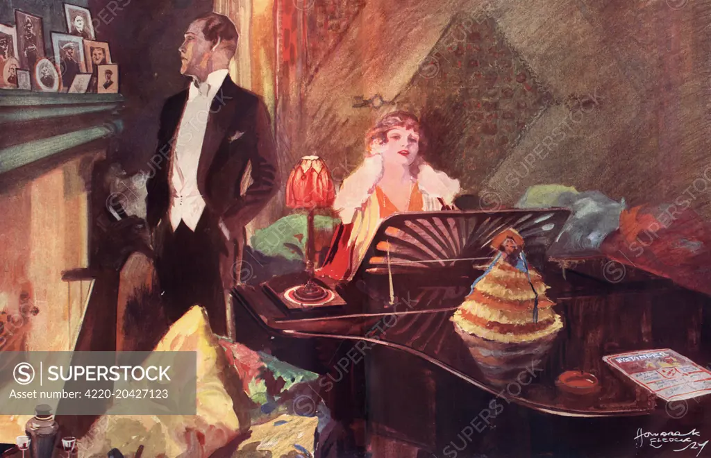 A lady in evening dress plays a grand piano, while a gentleman in white tie contemplates a group of framed portraits on the mantlepiece.  Note the copy of The Bystander on the grand piano.       Date: 1927