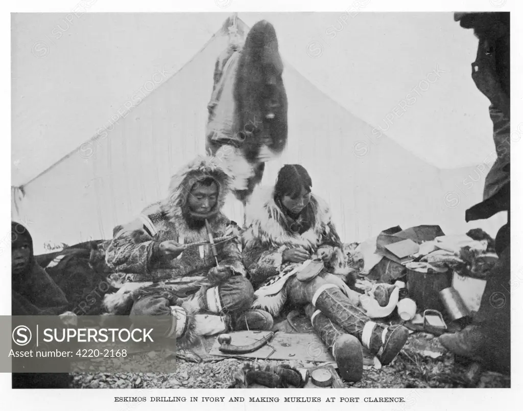 An Eskimo couple atPort Clarence, Alaska: he drills in ivory, she makes mukluksDate: 1900