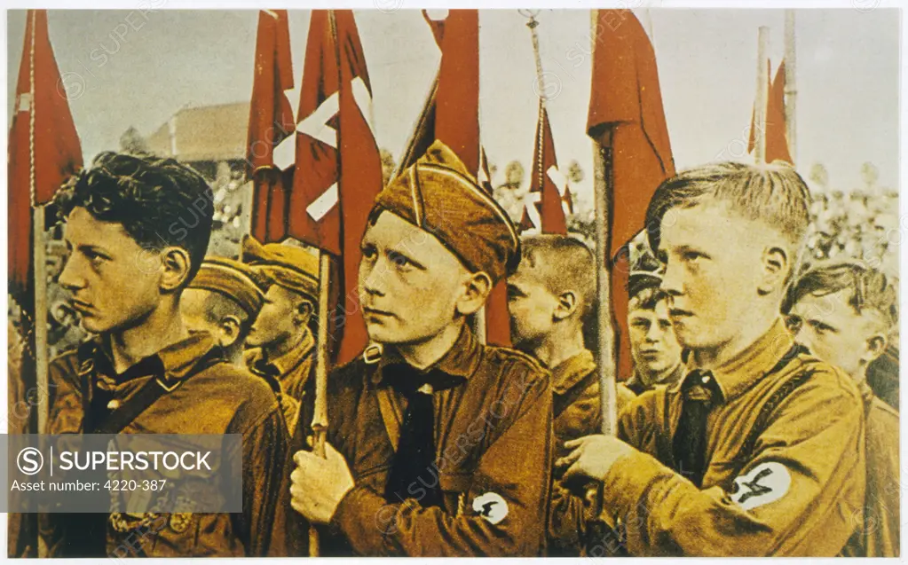 Members of the Hitler Jugend  on parade, carrying flags.