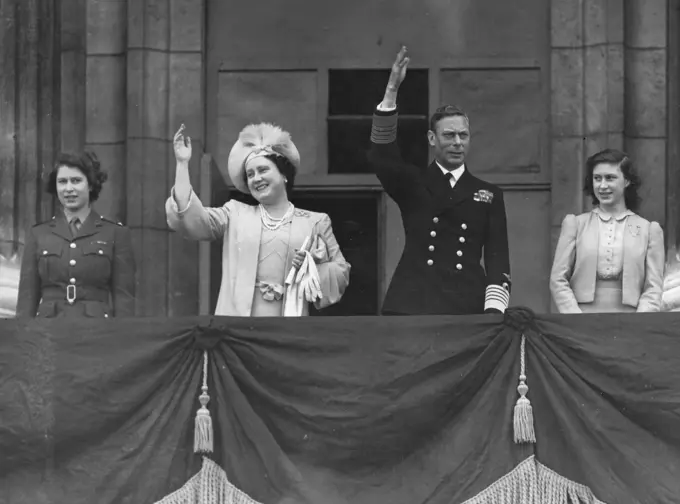 King George VI, Queen Elizabeth (later the Queen Mother) together with their daughters, Princess Elizabeth (later Queen Elizabeth II) in ATS uniform and Princess Margaret Rose on the balcony of Buckingham Palace waving to crowds on VE Day, 8 May 1945.     Date: 1945