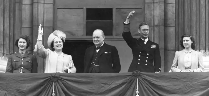 King George VI, Queen Elizabeth (later the Queen Mother) together with their daughters, Princess Elizabeth (later Queen Elizabeth II) in ATS uniform and Princess Margaret Rose, and Prime Minister, Winston Churchill, on the balcony of Buckingham Palace waving to crowds on VE Day, 8 May 1945.     Date: 1945
