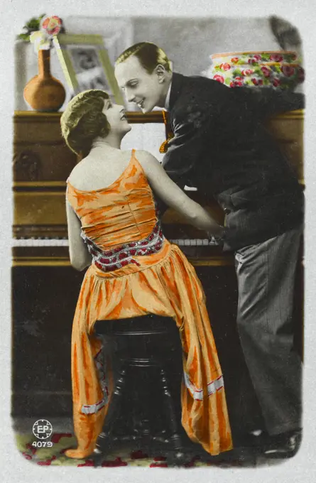  A lady plays the piano to  entertain her gentleman  friend: practice makes  perfect.      Date: 1920s
