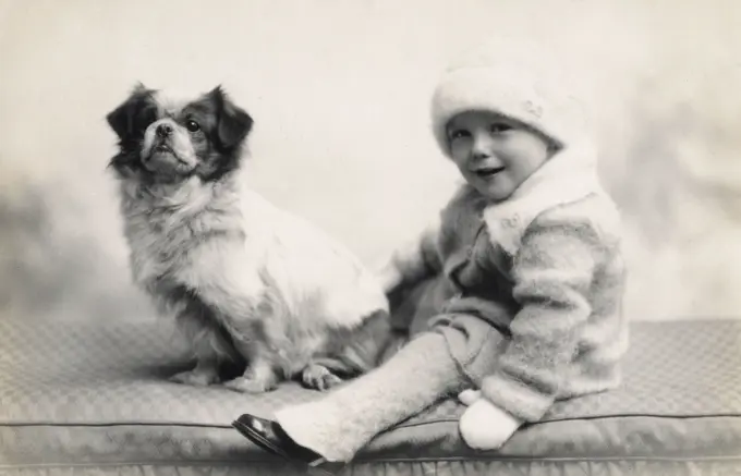 Studio portrait of toddler and dog.      Date: circa 1930s