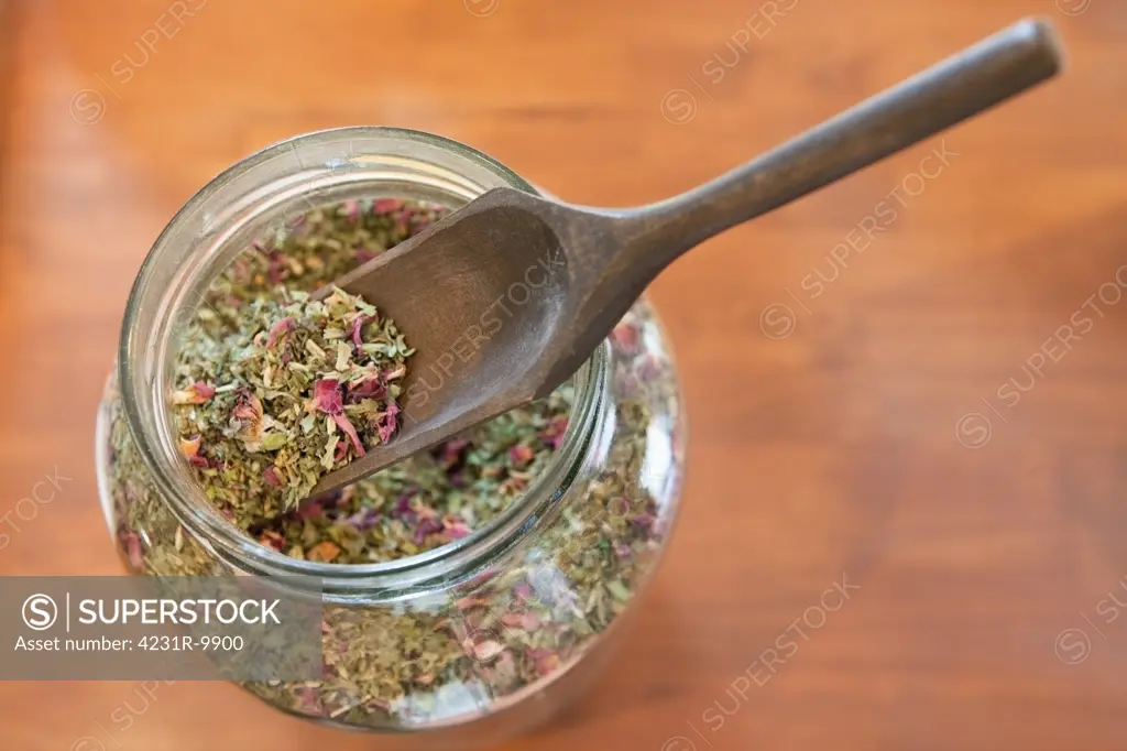 A glass jar and wooden scoop spoon,  full of aromatic seeds and dried herbs. Mixture. Plants and herbal remedies. A natural treatment and botanical supplier, an old fashioned Apothecary shop in Battle Ground, Washington, USA.