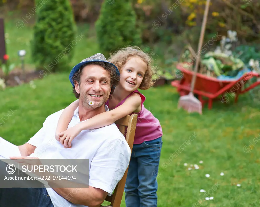 Smiling daughter hugs happy father in garden in summer