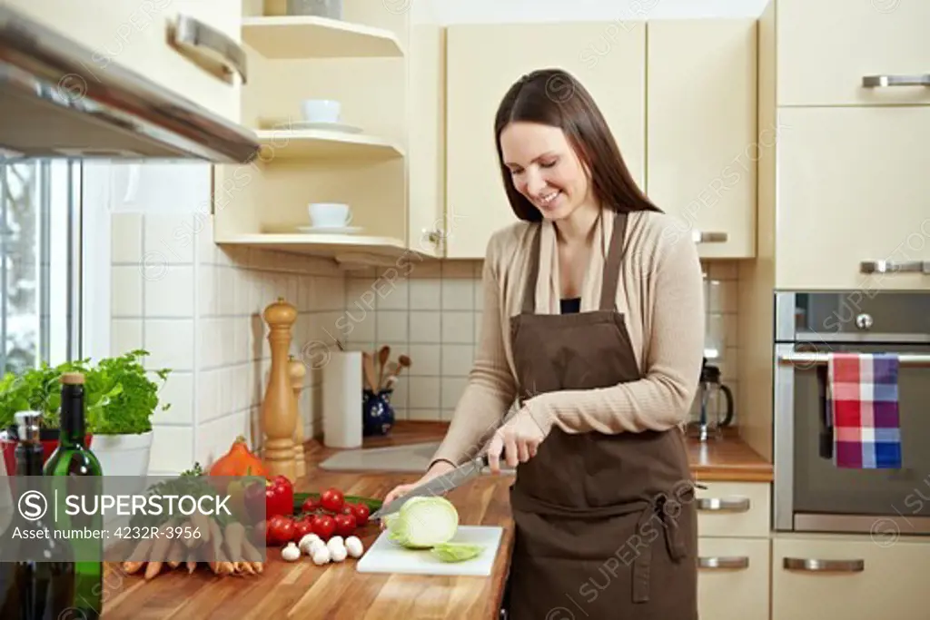 Happy woman cutting kohlrabi (Brassica oleracea var. gongylodes L.) in the kitchen