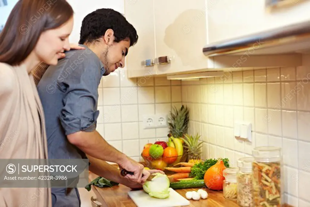 Woman watching man preparing vegetables in the kitchen